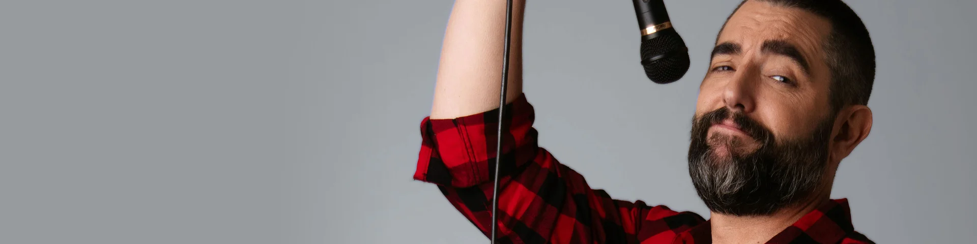 La imatge mostra Dani Mateo, està aixecant un micròfon amb una mà, com si estigués a punt de parlar o fer un monòleg